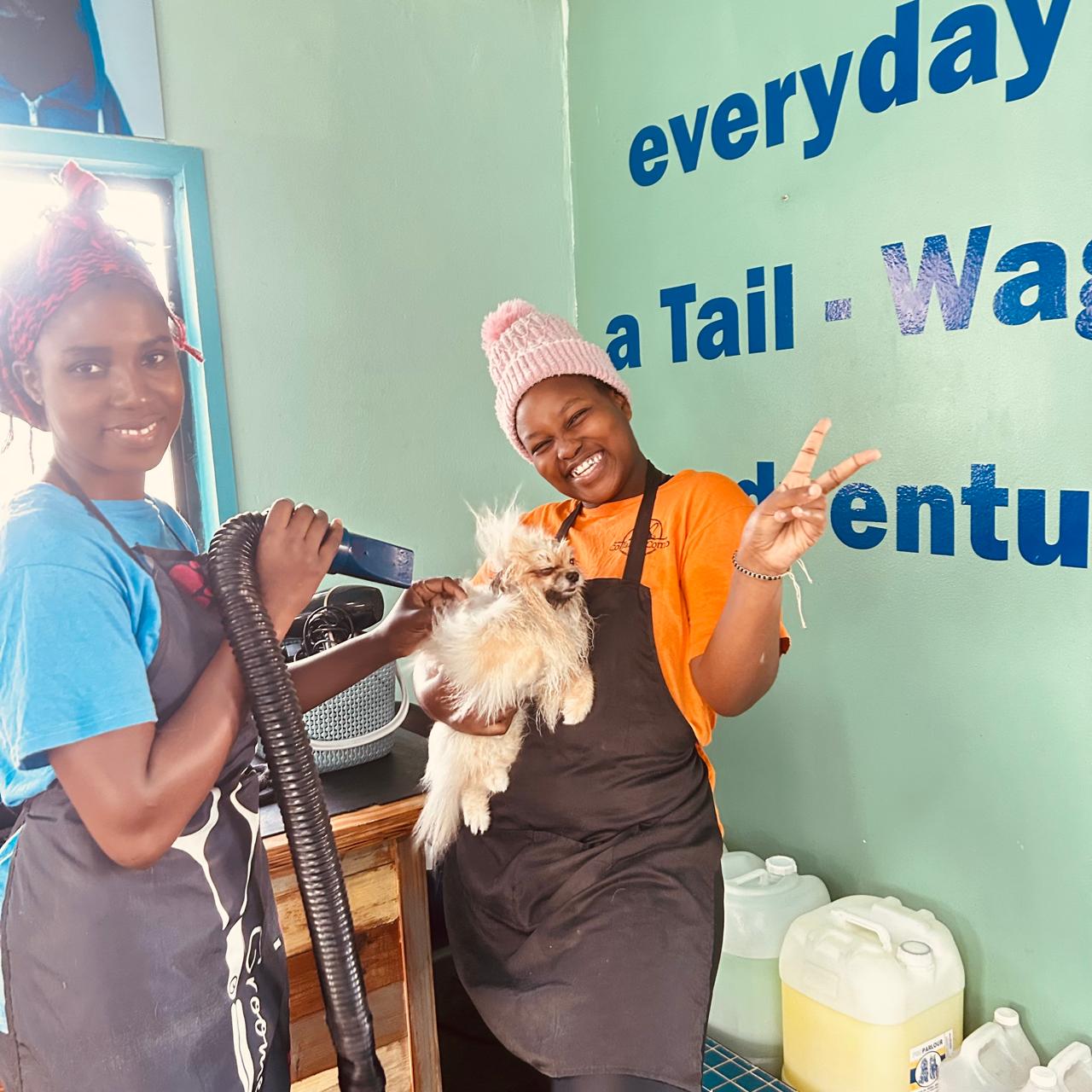 Two staff members with a freshly groomed dog